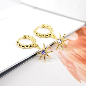Golden North Star earrings with purple zircon gemstone on minimalist white background