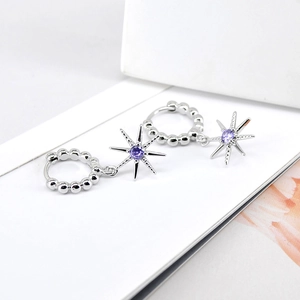 Macro shot of silver eight-point star earrings featuring vibrant purple zircon stones