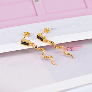 Detail view of golden snake earrings featuring square black zircon and scaled texture