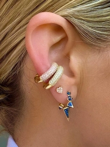 Close-up of stacked gold-plated ear cuffs with pink and yellow crystals and heart stud