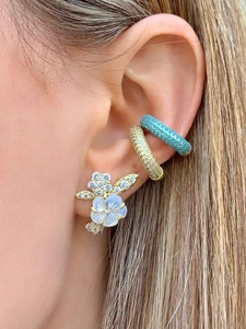 Close-up of gold flower stud with shell inlay and colorful crystal ear cuffs