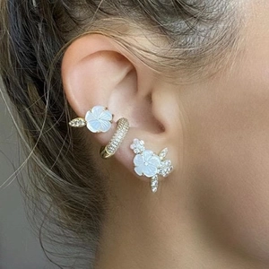 Detail of floral earring set with 18k gold plating and zircon inlay on model's ear