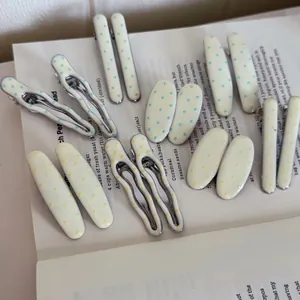 Barrettes à cheveux crème avec pois bleus et jaunes sur un fond de livre élégant
