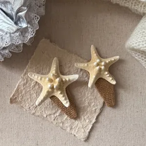 Detailed close-up of two starfish woven hair clips on elegant vintage background