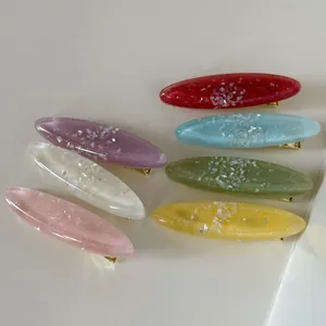 Gros plan détaillé sur des pinces à cheveux ovales en résine avec éclats de nacre