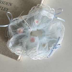 Détail du chouchou en mesh bleu clair avec bords en dentelle et broderie de roses