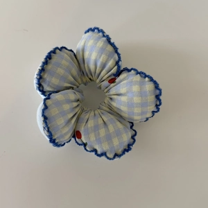 Detailed macro view of blue gingham scrunchie with cherry prints and crochet lace edges