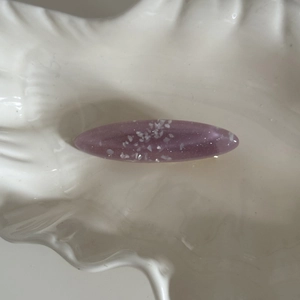 Vue macro d'une pince à cheveux ovale en résine violette avec paillettes brillantes