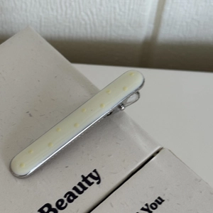 Vue détaillée d'une barrette rectangulaire crème à pois jaunes avec clip en métal