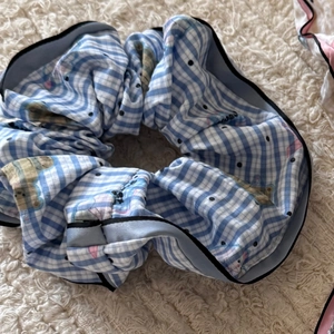 Blue gingham scrunchie with cute bear print and black trim on a soft plush surface