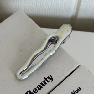 Vue détaillée de la barrette à pois bleus ondulée avec finition en résine crème