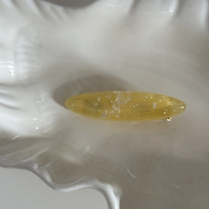 Vue macro de la pince à cheveux ovale jaune avec paillettes sur plateau en nacre