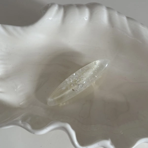 Détail macro d'une pince à cheveux ovale en résine translucide avec des paillettes
