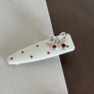 Detail of cream drop hair clip with red polka dots and silver cherry bow embellishment