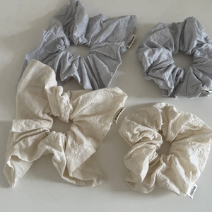 Détail de quatre chouchous en coton avec broderie florale et étiquettes sur fond blanc