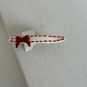 Detail of a red bow hair clip with dotted edges and polished enamel finish
