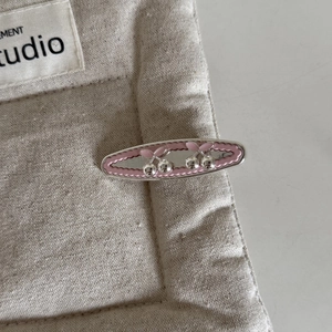 Silver cherry rhinestone hair clip with pink macaron wavy edge on beige linen fabric
