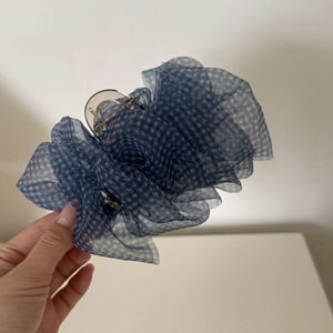 Detailed close-up of a blue gingham seersucker hair claw with ruched organza fabric texture