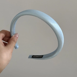 Detailed macro view of the handmade label on a padded light blue satin headband