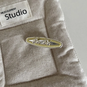 Detailed view of a silver cherry hair clip with yellow wavy pattern and metal cherry accent