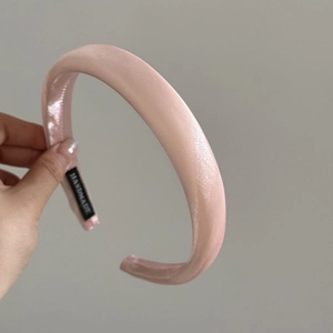 Close-up of pink satin silk headband featuring a handmade label on the inner side