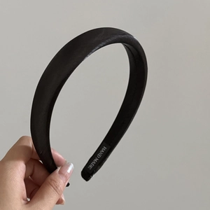 Detail of black satin headband with handmade woven label showing fine silk texture