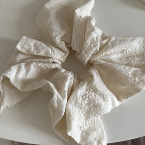 Gros plan d'un chouchou blanc avec broderie florale délicate et détails de texture