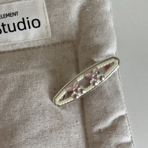 Detail of sweet cream hair clip with pink cherry and silver bead on linen texture