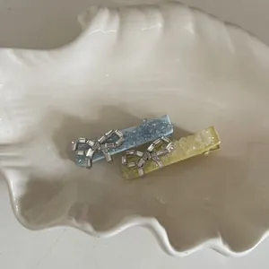 Detail of sweet blue and yellow bow hair clips with crushed rhinestones in shell tray
