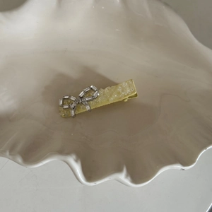 Yellow bow hair clip with crushed ice crystal texture and silver rhinestone bow accent