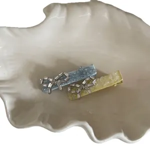 Sparkly yellow and blue bow hair clips with crushed crystal finish on white shell plate