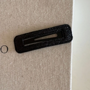 Elegant rectangular black glitter hair clip with shimmering texture for a stylish women look