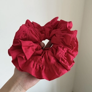 Macro detail of large red layered ruffle satin scrunchie with soft pleated texture