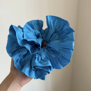 Detail of large double-layer satin ruffle scrunchie in bright blue fabric texture