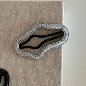 Macro shot of wavy glitter hair clip showing silver sparkle texture and fine stitching detail