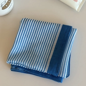 Detail view of a blue and white striped square headscarf with refined stitching edges