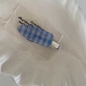 Détail d'une pince à cheveux à carreaux bleus et blancs sur une étiquette vintage