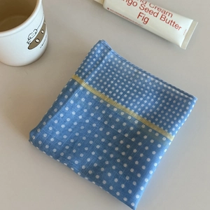 Detailed view of blue polka dot scarf featuring fine fabric texture and yellow accent stripe
