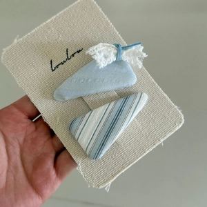 Dettaglio di fermagli in tessuto blu menta con fiocco in pizzo su supporto in tela
