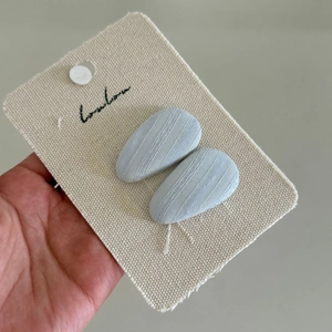 Dettaglio di due fermagli per capelli in tessuto a coste blu menta su cartoncino