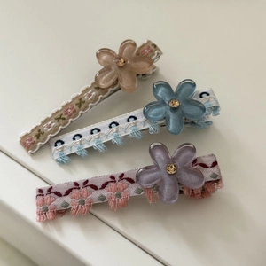 Dettaglio di tre fermagli per capelli a fiore fatti a mano con ricami e petali in resina