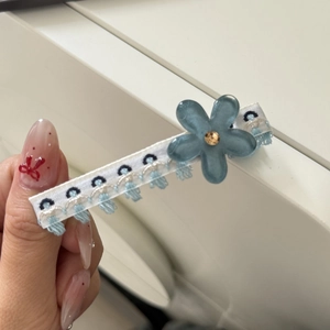 Dettaglio del fermaglio per capelli floreale con petalo ricamato blu e perla dorata