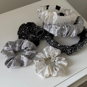 Detail showing satin scrunchies and headbands with rhinestones in white, black and silver