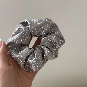 Silver grey satin scrunchie with sparkling rhinestones held by hand for accessories