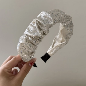 Detailed close-up of cream pleated satin headband with handcrafted crystal rhinestones