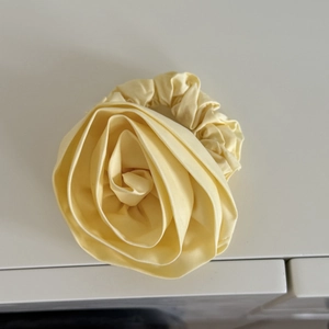 Detail view of a handcrafted 3D yellow fabric rose flower hair scrunchie for women