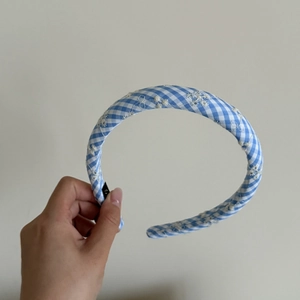 Détail d'un serre-tête vichy bleu et blanc avec broderie de fleurs blanches