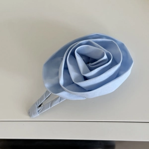 Detailed top view of handmade light blue satin rose hair clip with layered petals