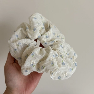 Chouchou brodé avec motif floral bleu sur tissu en coton blanc léger