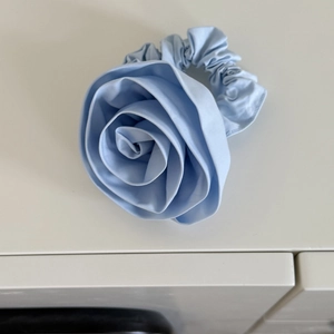 Detailed close-up of light blue handmade rose scrunchie with layered fabric petals